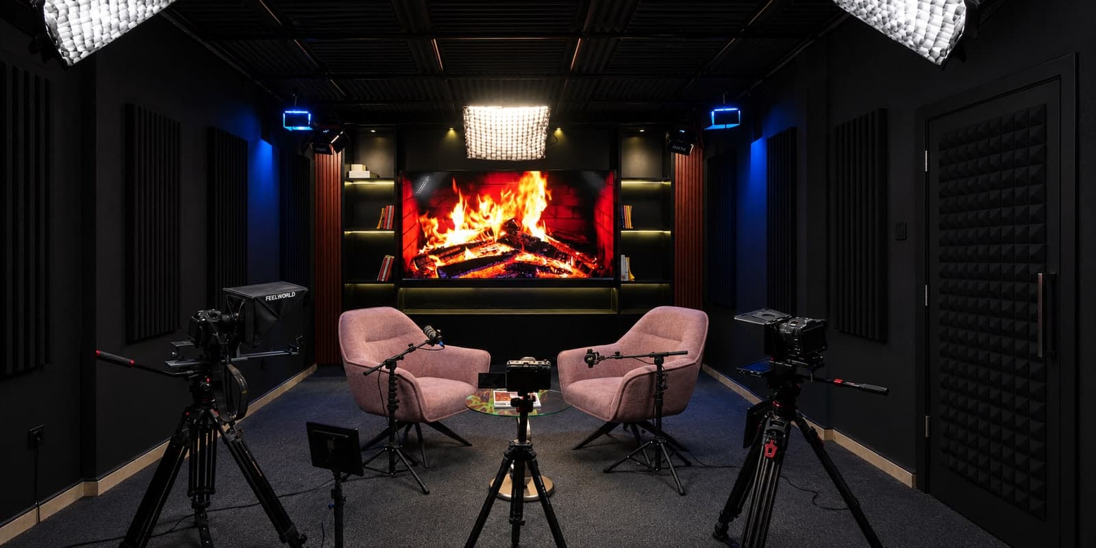 The studio set seen from the entrance: the fireplace on the screen, pink armchairs, cameras, and the acoustic door on the right